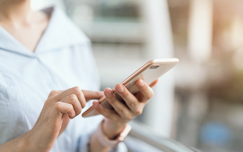 Frau hält Smartphone in der Hand und symbolisiert den einfachen Online-Zugriff
