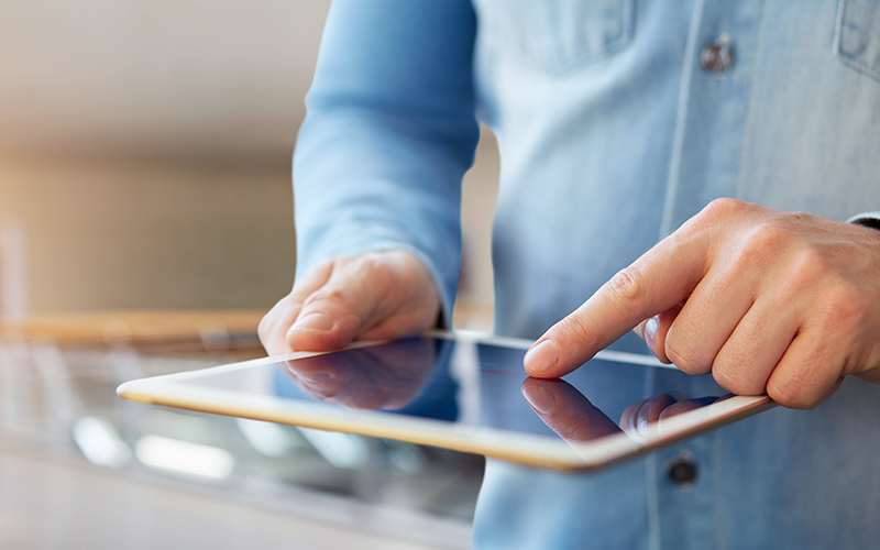 Mann tippt auf Tablet zur Nutzung des Online-Kundencenters
