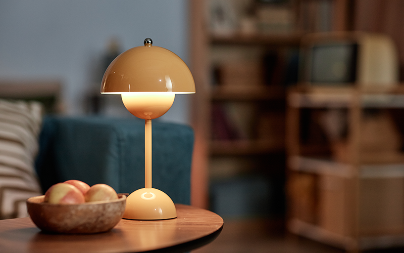 Wohnzimmersituation mit einem Tisch, auf dem eine Lampe und eine Obstschale stehen.