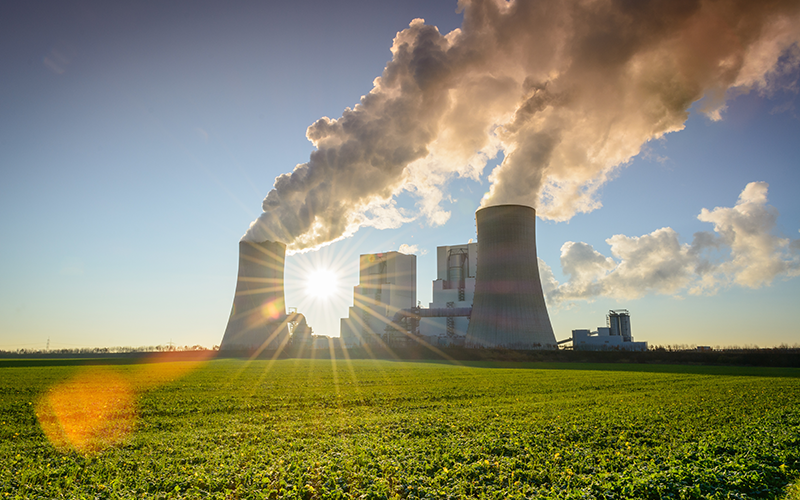 Kraftwerk inmitten blauem Himmel und grüner Wiese