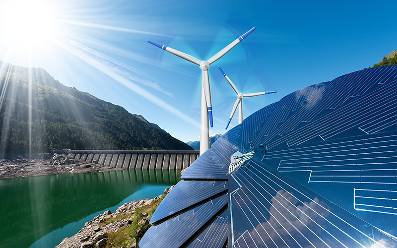 Bergkulisse mit See und Staudamm, davor Windräder und Photovoltaik