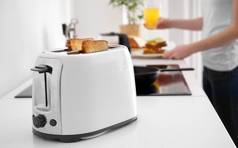 Frühstückszubereitung: Toast im Toaster und Mann mit Glas und Teller